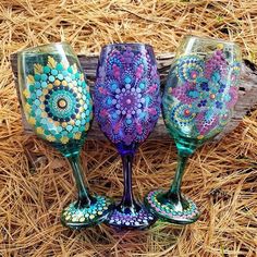 three hand painted wine glasses sitting on top of straw bales in front of hay