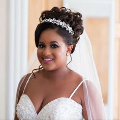 a woman wearing a bridal gown and veil smiles at the camera while standing in front of a doorway