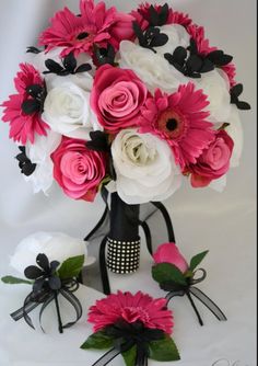 a vase filled with pink and white flowers on top of a table next to black ribbon