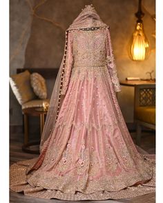 a woman in a pink lehenga with gold embroidery on the sleeves and back