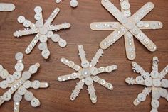 four snowflakes made out of buttons on top of a wooden table next to each other