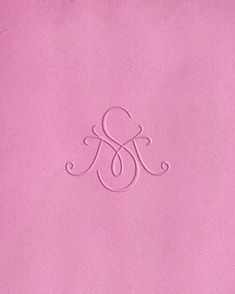 a close up of a pink paper with a monogrammed symbol on the front