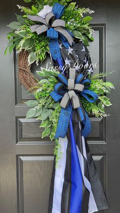 a patriotic wreath with blue, white and black ribbons hanging on the front door for memorial day