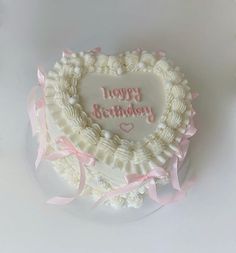 a heart shaped birthday cake with pink ribbon