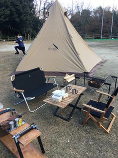 a tent set up in the middle of a field with chairs and tables around it