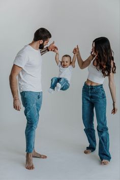 a man and woman holding a baby up in the air while standing next to each other