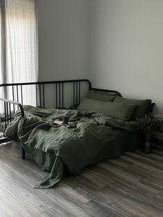 an unmade bed with green sheets and pillows