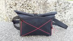 a black and red bag sitting on top of a cement ground next to a stone wall