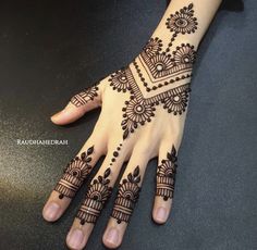 a hand with henna tattoos on it, and the design is done in black ink