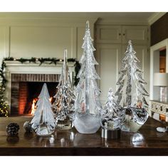 three glass christmas trees sitting on top of a table next to a fire place in a living room