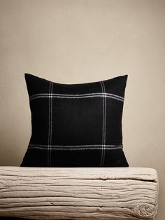 a black and white plaid pillow sitting on top of a wooden table next to a wall