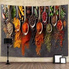 spoons full of spices hanging on a wall in front of a table with a lamp