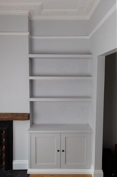 an empty room with white bookcases and a fireplace in the corner is shown