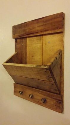 a wooden box mounted to the side of a wall with two hooks on each side