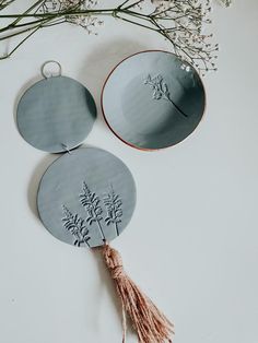 two plates with designs on them sitting next to a flower vase and some dried flowers