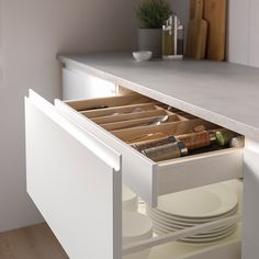 an open drawer in a kitchen with plates and utensils