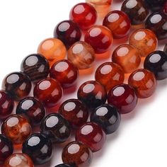 multicolored glass beads are lined up on a white surface, one is red and the other is brown