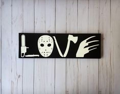 a wooden sign that says love with a mask and knife in the shape of a face