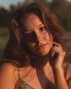 a woman in a floral dress posing for a photo with her hand on her chin