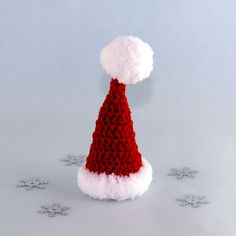 a red and white knitted santa hat sitting on top of snow flakers