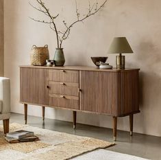 a living room with a couch, table and vases on top of the dresser