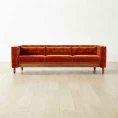 an orange couch sitting on top of a hard wood floor next to a white wall