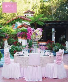 the table is set with white linens and pink flowers