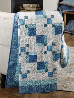 a blue and white quilt sitting on top of a couch next to a fire place