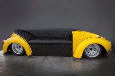 a yellow and black car shaped couch sitting on top of a metal floor next to a gray wall