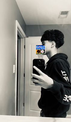 a man taking a selfie in the mirror with his cell phone and stickers on it