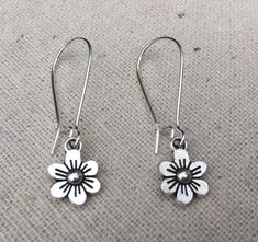 These are just so sweet and cute!  Little daisy dangle earrings.  Perfect addition to any outfit and sure to brighten your day!Made from allergy free plated silver.  The flowers measure 1/2” long by 3/8” wide and hang from 1” kidney style ear wires that lock and latch.  Overall drop length is 1 1/2”.  Thanks for stopping by!  Please take a moment and visit the rest of my Etsy shop.  I have many more unique jewelry designs to choose from!🌸 Tiger Flower Jewelry 🌸  🌸 Inspired by Nature 🌸 Whimsical Spring Flower Earrings With Ear Wire, Dainty Adjustable Flower Earrings For Spring, Spring Sterling Silver Earrings With Flower Charm, Whimsical Adjustable Flower Charm Earrings, Nickel-free Daisy Earrings For Gifts, Cute Flower Shaped Hypoallergenic Earrings, Cute Hypoallergenic Flower-shaped Earrings, Cute Hypoallergenic Flower Shaped Earrings, Everyday Dangle Earrings With Flower Charm