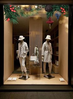 two mannequins dressed in white clothes and hats are standing in front of a store window