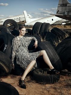 a woman sitting on top of tires in front of an airplane