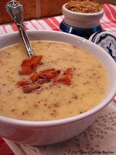 a white bowl filled with soup and bacon on top of a red and white table cloth