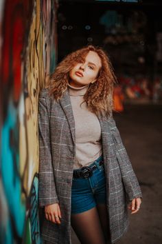 a woman leaning against a wall with graffiti on it