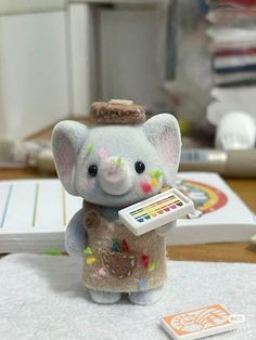 an elephant figurine holding a paintbrush on top of a table next to a remote control