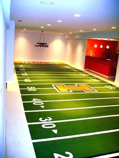 an empty football field with lights on and numbers painted on the ground in front of it