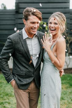 a man and woman standing next to each other in front of a house with confetti falling from the air