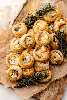 small appetizers are arranged on top of brown parchment paper with rosemary sprigs