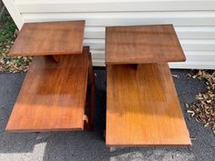 two wooden tables sitting next to each other on top of a cement ground in front of a house