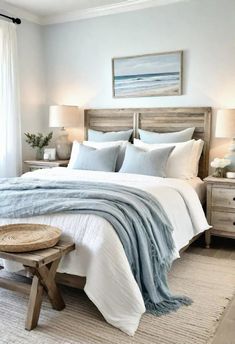 a bedroom with white and blue bedding, two nightstands and a painting on the wall