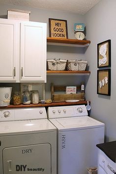 a washer and dryer in a small room with shelves on the wall above them