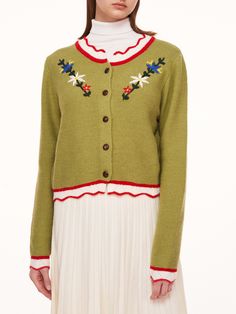 a woman in a green sweater and white skirt Green Cotton Winter Cardigan, Green Cotton Cardigan For Winter, Green Knitted Cotton Cardigan, Green Cotton Cardigan For Fall, Green Cotton Sweater For Spring, Spring Green Cotton Sweater, Fitted Green Cotton Cardigan, Spring Green Knitted Outerwear, Knitted Green Outerwear For Spring