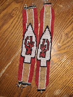 two red and white beaded wristbands sitting on top of a wooden floor