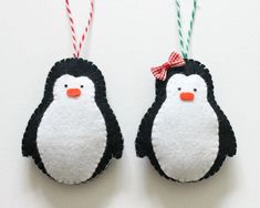 two felt penguin ornaments hanging from twine