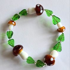 I Handmade This Bracelet Using Glass Mushroom Beads And Glass Leaf Beads, Strung On Strong And Stretchy Elastic Cord. Colors Are : Brown, White, Green, And Clear. Fits A Medium To Larger Wrist Best. See Photo Next To Quarter For Size Reference Ships Fast! Buffh8388jw3b5l2 Beaded Forest Forestcore Cottage Cottagecore Fungus Fungi Mycology Women's Hand Crafted Aminata Spotted Spots Polka Dot Jewelry Goblincore Accessories, Goblincore Crafts, Cottagecore Bracelet, Mushroom Bracelet, Goblin Fairy, Mushroom Beads, Goblincore Fairycore, Cottagecore Jewelry, Leaf Beads