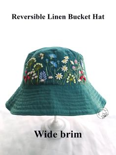 the reversible linen bucket hat has flowers on it and is green with white daisies