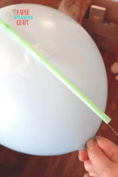 a person is holding a plastic balloon with a green straw sticking out of the top