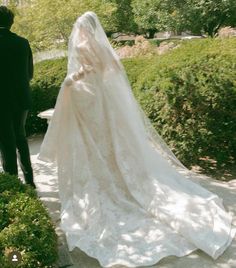 a bride and groom walking down a path in the park with their back to the camera