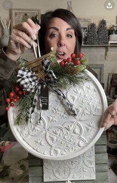 a woman holding up a large white plate with decorations on it